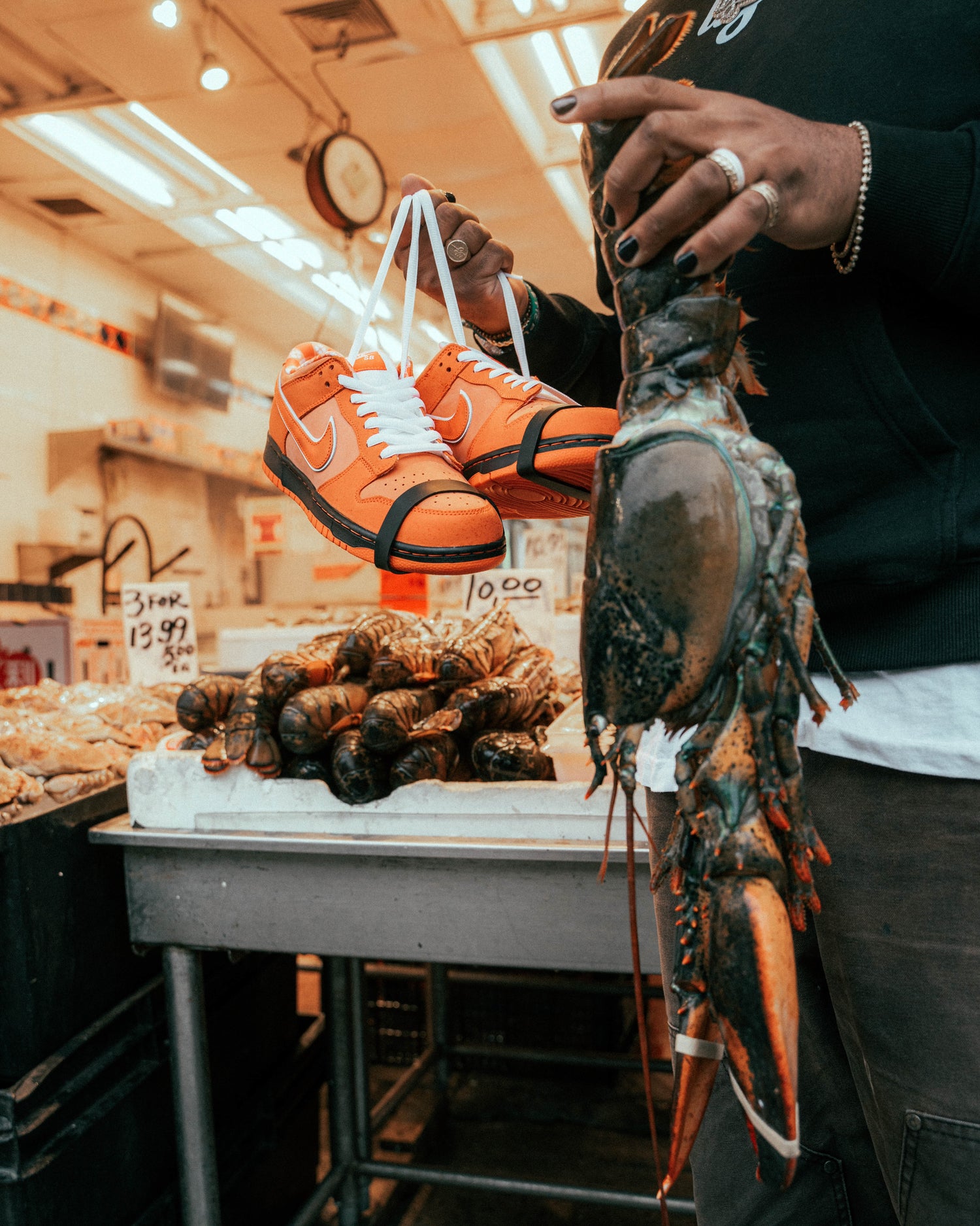 Detalle de calzado naranja y una langosta en una composición de mercado.